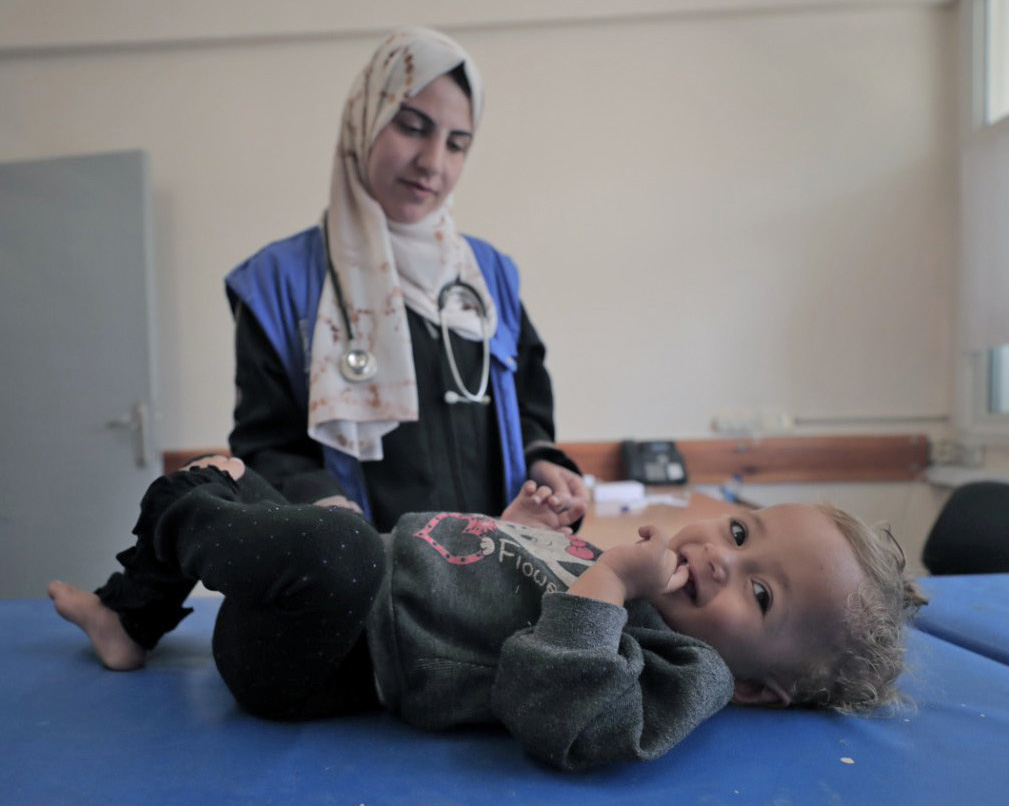 May 26, 2024, Rafah: A staff member from the UNRWA Health Team at the Tel Al-Sultan Health Center in Rafah area conducts a medical examination for a displaced child.© 2024 UNRWA Photo by Mohammed Hinnawi