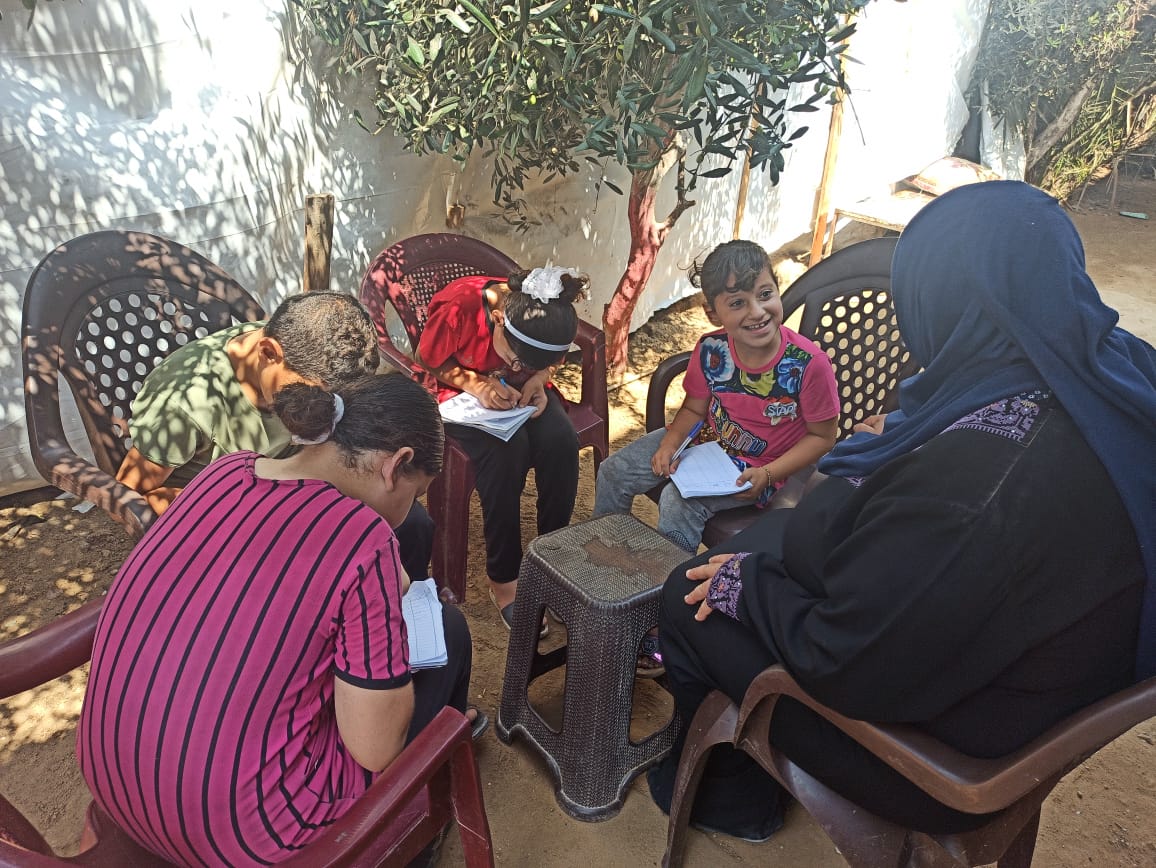 Ghada and her children sitting on the newly bought plastic chairs, September 2020. Photo by SIF