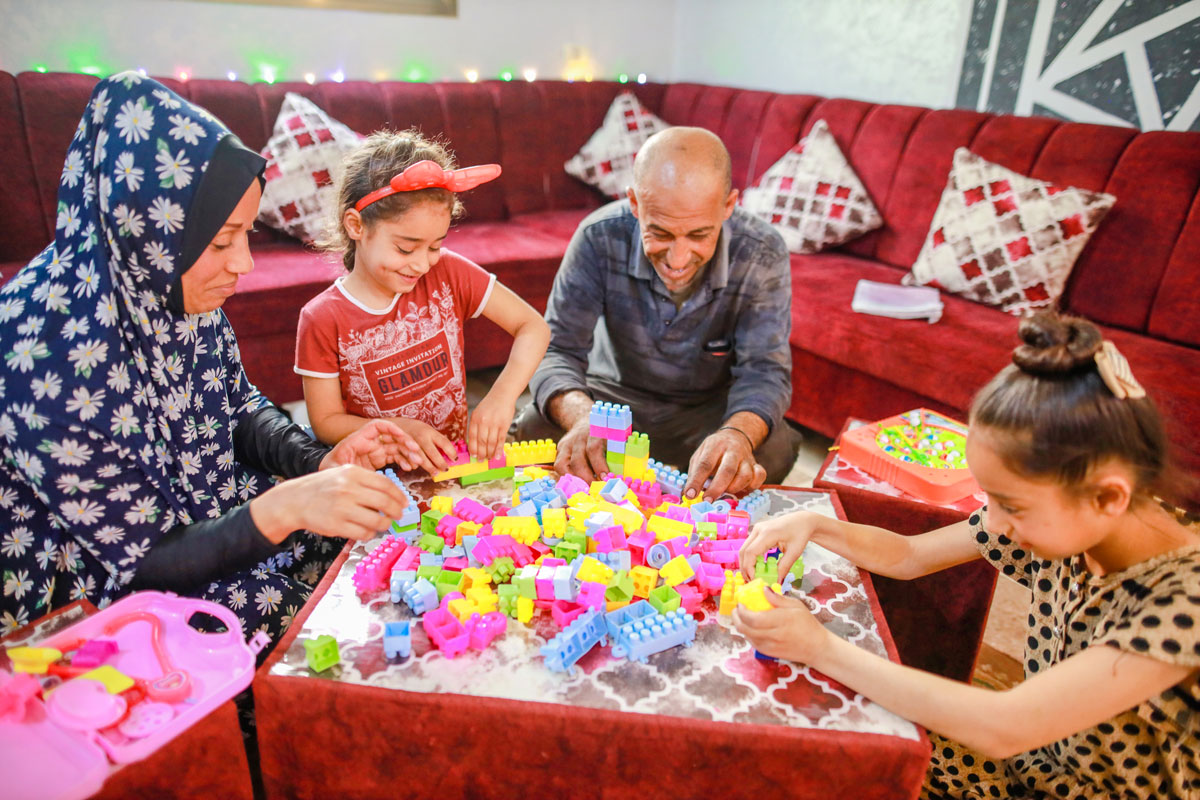 Asma and Sade playing with two of their daughters in their renovated livingroom.