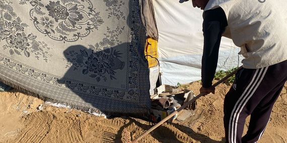 Aid worker leveling sand in a makeshift collective shelter in Gaza, to strengthen flood resilience and improve access to essential services ahead of the rainy season. Photo by CESVI