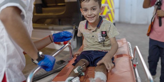 An aid worker supporting the medical evacuation of an injured child in the Gaza Strip. Photo by WHO
