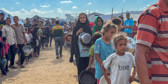 Displaced families queue for a hot meal distribution at a community kitchen in Deir al Balah, Gaza, in October 2025. With renewed hope for a ceasefire, the UN stands ready to scale up life-saving aid delivery across the Gaza Strip. Photo: OCHA/Olga Cherevko