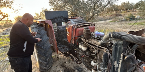 "הטרקטור שלי היה הכול בשבילי העבודה שלי ובשביל הפרנסה של המשפחה שלי." איאד, חקלאי פלסטיני מבורקה, בנפת שכם, עומד ליד הטרקטור שלו, שהוצת על ידי מתנחלים בתחילת דצמבר 2025. צילום: משרד האו"ם לתיאום עניינים הומניטריים.