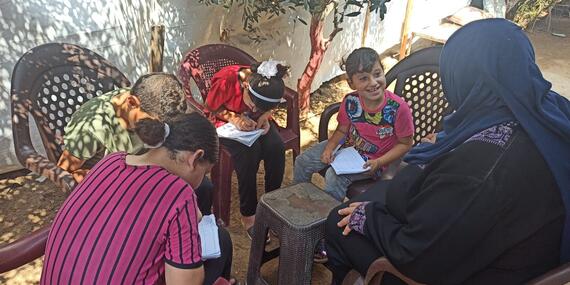 Ghada and her children sitting on the newly bought plastic chairs, September 2020. Photo by SIF