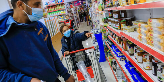 Jaber and his daughter select the groceries they need most, for which they would pay with an CRS electronic voucher. Photo by Mohamed Reefi for CRS