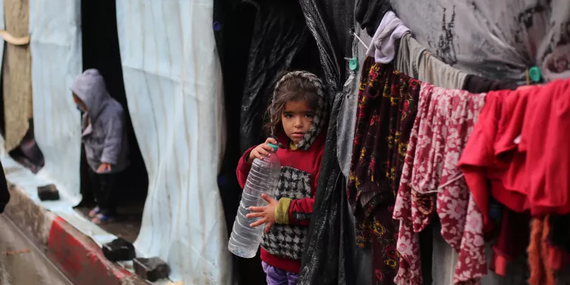طفلان نازحان أمام مسكنيهما المؤقتين في غزة. تصوير اليونيسف/البابا