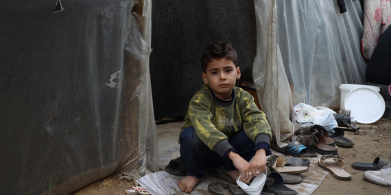 فتى فلسطيني يجلس بجوار مبنى مؤقت في منشأة تعليمية لجأت الأسر النازحة إليها في غزة. تصوير اليونيسف/البابا