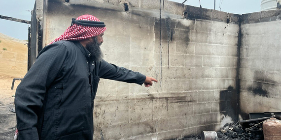 أحد سكان قرية بردلة الفلسطينية يشير إلى منزله الذي أحرقه المستوطنون الإسرائيليون، حيث أدّى الحريق المتعمد إلى تدمير المنازل وحظائر الحيوانات، مما أسفر عن تهجير أسرتين وتقويض سبل عيشهم. تصوير مكتب الأمم المتحدة لتنسيق الشؤون الإنسانية.