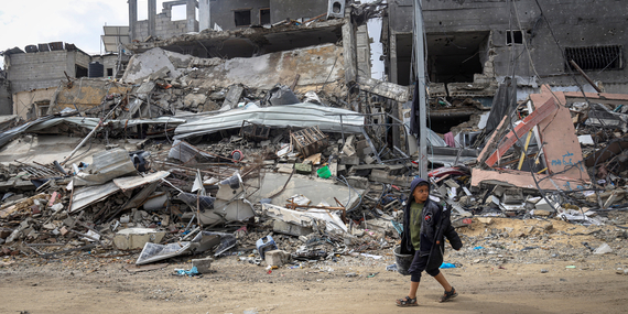 تامر البالغ من العمر تسعة أعوام يمشي فوق أنقاض حيّه المدمّر في خانيونس. تصوير اليونيسف/إياد البابا