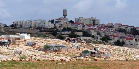 Houses in the Palestinian Bedouin community of Arab al Jahalin al Jabal, east of Jerusalem, against the backdrop of the Israeli settlement of Ma’ale Adummim. © Photo by OCHA.