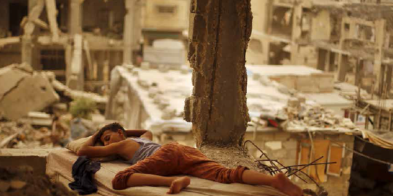 Palestinian boy sleeping inside his destroyed home in the Shuja’iyeh neighbourhood of Gaza City, September 2015. Photo by Suhaib Salem/