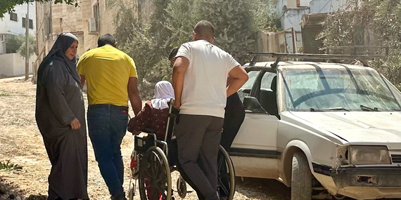 امرأة فلسطينية مسنّة على كرسي متحرك تتنقل في شارع مدمر في جنين في طريقها إلى المستشفى، عقب عملية نفذتها القوات الإسرائيلية على مدار عشرة أيام. تصوير مكتب الأمم المتحدة لتنسيق الشؤون الإنسانية، 8 أيلول/سبتمبر 2024