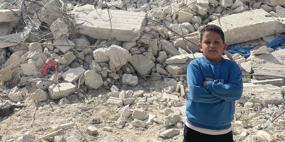 فتى فلسطيني يقف أمام منزله الذي كان قيد الإنشاء ولكن هدمته السلطات الإسرائيلية بحجة افتقاره إلى رخصة بناء صادرة عن إسرائيل في بيت أُمَّر. تصوير مكتب الأمم المتحدة لتنسيق الشؤون الإنسانية، 14 تشرين الثاني/نوفمبر 2024