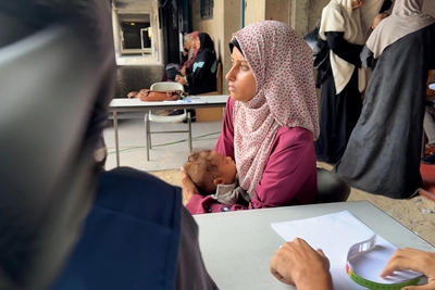 Seven-month-old Iman, with her mother, at a medical point in a school-turned-shelter in Gaza city. She was diagnosed with severe acute malnutrition at six months and UNRWA health teams have been providing her with emergency treatment and supplementary food. Photo by © 2025 UNRWA