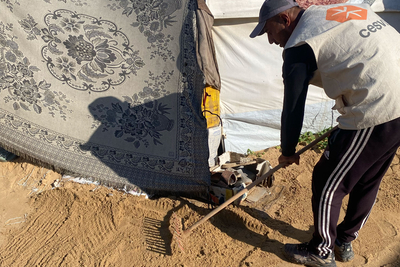 Aid worker leveling sand in a makeshift collective shelter in Gaza, to strengthen flood resilience and improve access to essential services ahead of the rainy season. Photo by CESVI