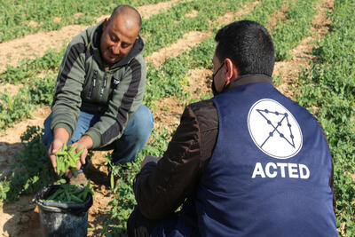 Omar on his field with a staff member from ACTED.