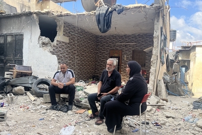 أسرة فلسطينية مهجّرة تجلس وسط أنقاض منزلها المدمر في مخيم طولكرم للاجئين في أعقاب عملية إسرائيلية. تصوير مكتب الأمم المتحدة لتنسيق الشؤون الإنسانية، 7 أيلول/سبتمبر 2024