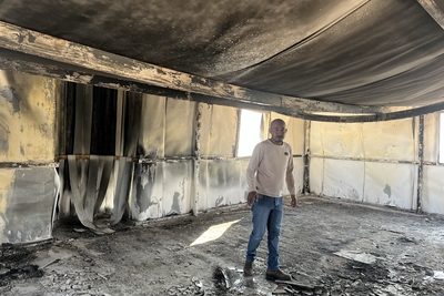 سليمان مليحات، راعي يقطن في تجمع المعرجات البدوي الشرقي في أريحا، يقف في مسجد التجمع الذي أضرم المستوطنون الإسرائيليون النار فيه في 2 شباط/فبراير 2025. كما احترق جراره الذي كان يستخدمه لنقل المياه أثناء الهجوم. تصوير مكتب الأمم المتحدة لتنسيق الشؤون الإنسانية.