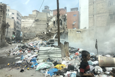 فتى يمشي بجانب النفايات الصلبة المتناثرة في منطقة لحقت بها أضرار جسيمة في مدينة غزة. تصوير مكتب الأمم المتحدة لتنسيق الشؤون الإنسانية/أولغا تشيريكوف، 25 نيسان/أبريل 2024