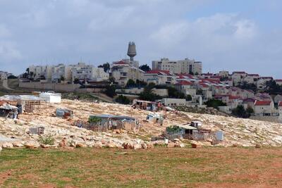 Houses in the Palestinian Bedouin community of Arab al Jahalin al Jabal, east of Jerusalem, against the backdrop of the Israeli settlement of Ma’ale Adummim. © Photo by OCHA.