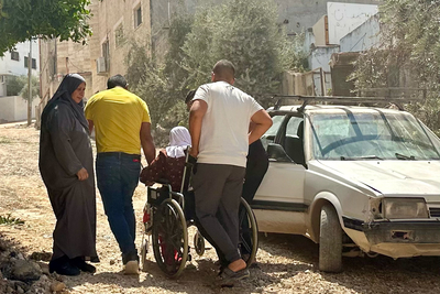 امرأة فلسطينية مسنّة على كرسي متحرك تتنقل في شارع مدمر في جنين في طريقها إلى المستشفى، عقب عملية نفذتها القوات الإسرائيلية على مدار عشرة أيام. تصوير مكتب الأمم المتحدة لتنسيق الشؤون الإنسانية، 8 أيلول/سبتمبر 2024