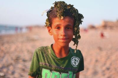 فتى فلسطيني بعد أن سبح على شاطئ ملوث في مخيم دير البلح للاجئين، غزة © - تصوير رهف بطنيجي، منظمة أوكسفام، 2018